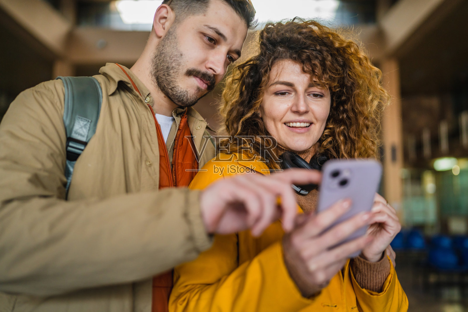 年轻情侣在车站等火车时使用手机照片摄影图片