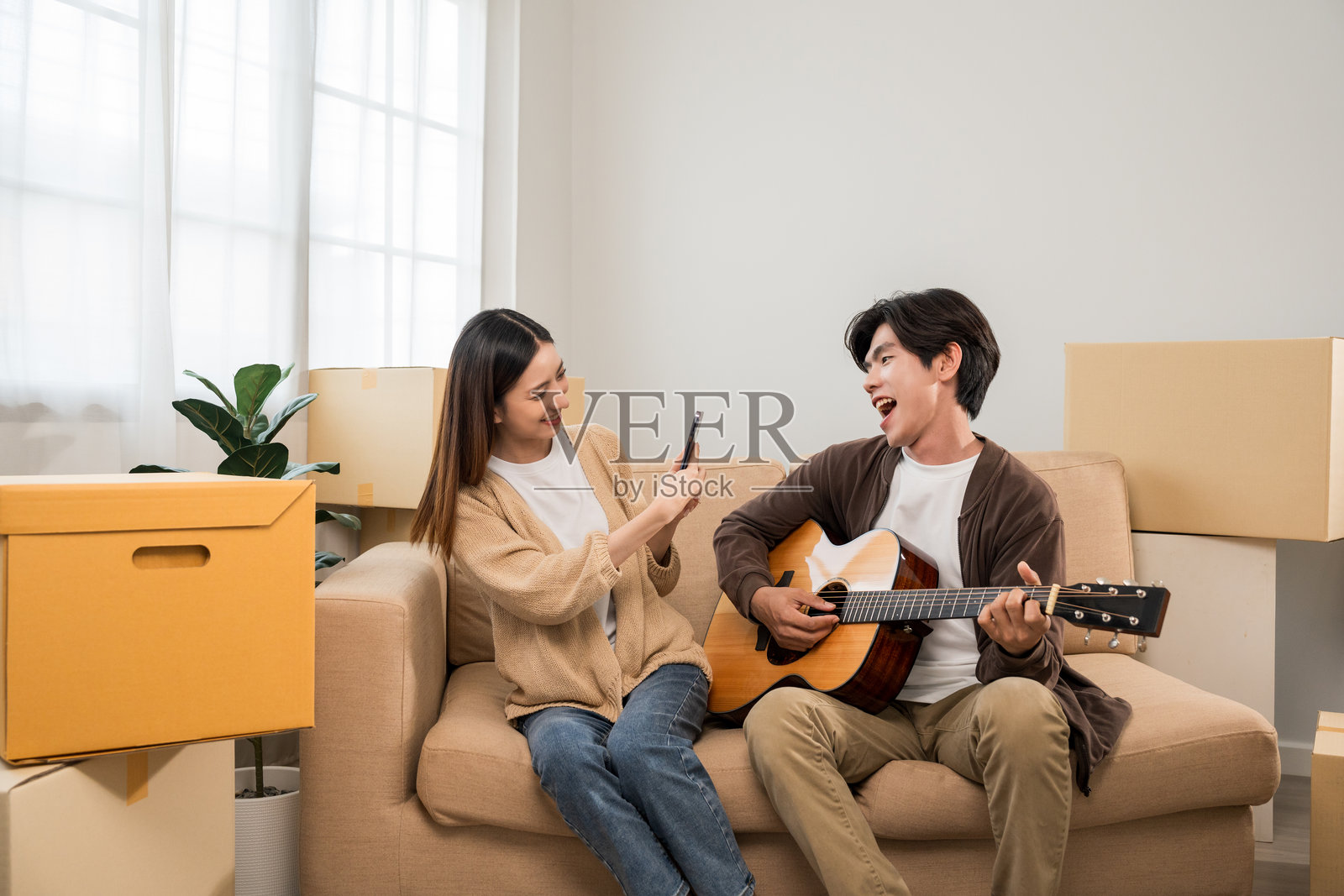亚洲家庭夫妇购买新房。男人和女人快乐地搬入新家,搬运包裹并进行装饰,搬家时有很多纸箱。照片摄影图片