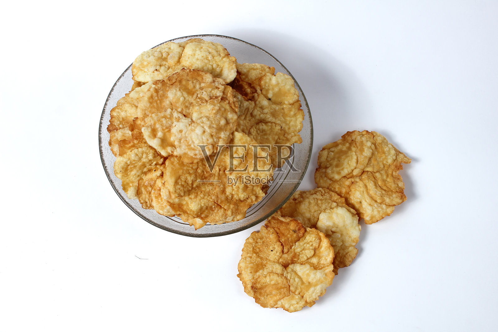 甜味的 emping 饼干放在玻璃碗中,背景为白色。emping 饼干是由 melinjo 果实制成的,属于印尼的传统小吃。照片摄影图片