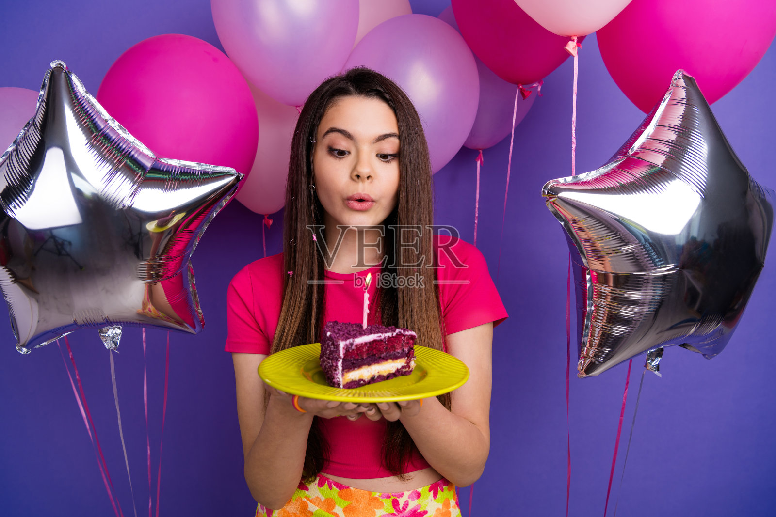 年轻女性穿着色彩缤纷的服装,在充满活力的背景下享受与气球和蛋糕片的节日时刻。照片摄影图片