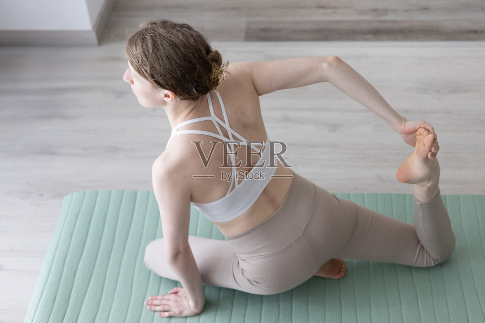 年轻女性在客厅里做瑜伽普拉提,旁边有舒适的沙发和装饰品照片摄影图片