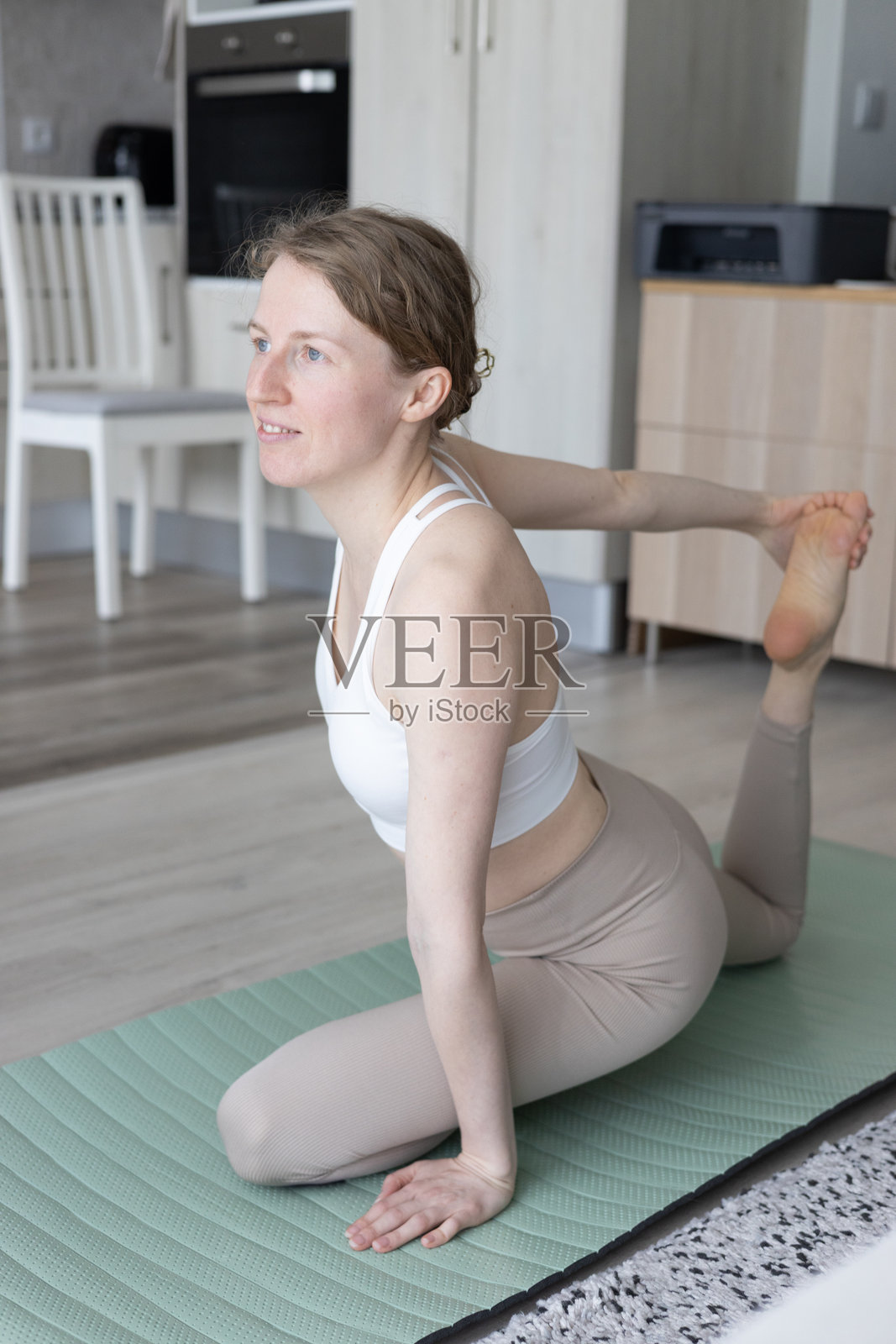 年轻女性在客厅里做瑜伽普拉提,旁边有舒适的沙发和装饰品。照片摄影图片