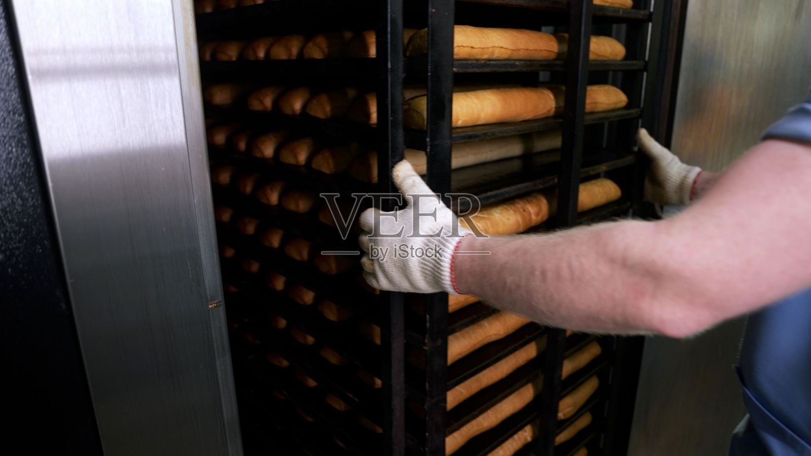 面包师将面包放置在工业烤箱的架子上照片摄影图片