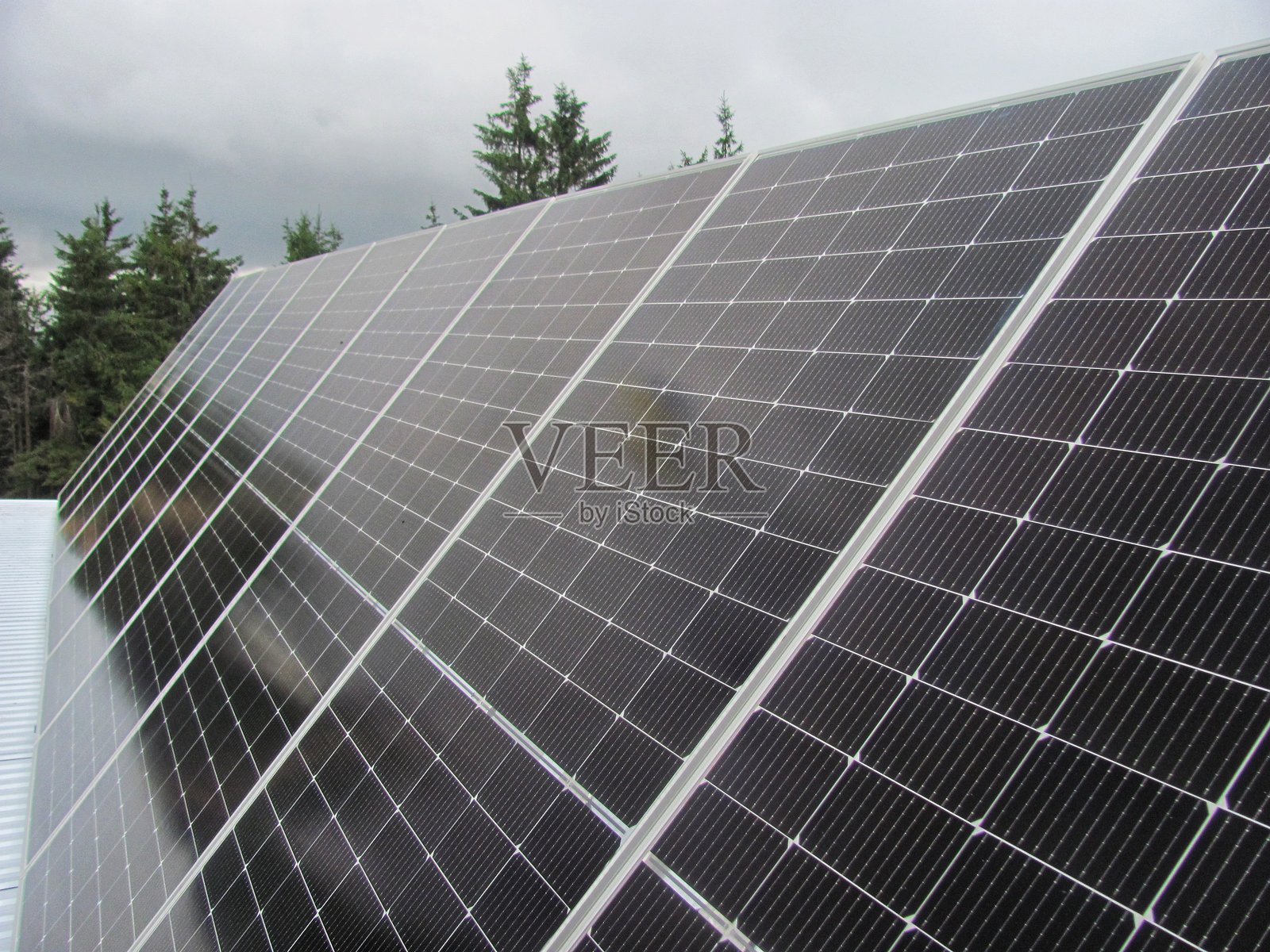 森林旁的小屋上安装了太阳能电池板照片摄影图片