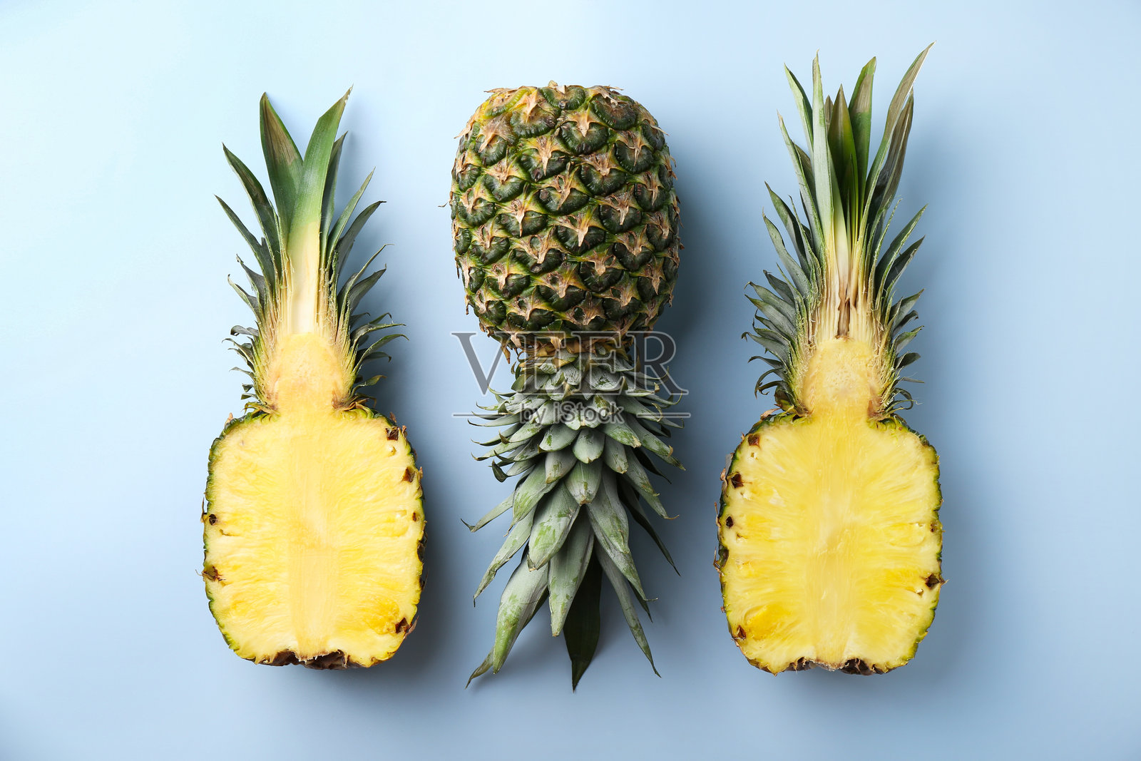 整颗和切开的菠萝在浅蓝色背景上,平铺展示照片摄影图片