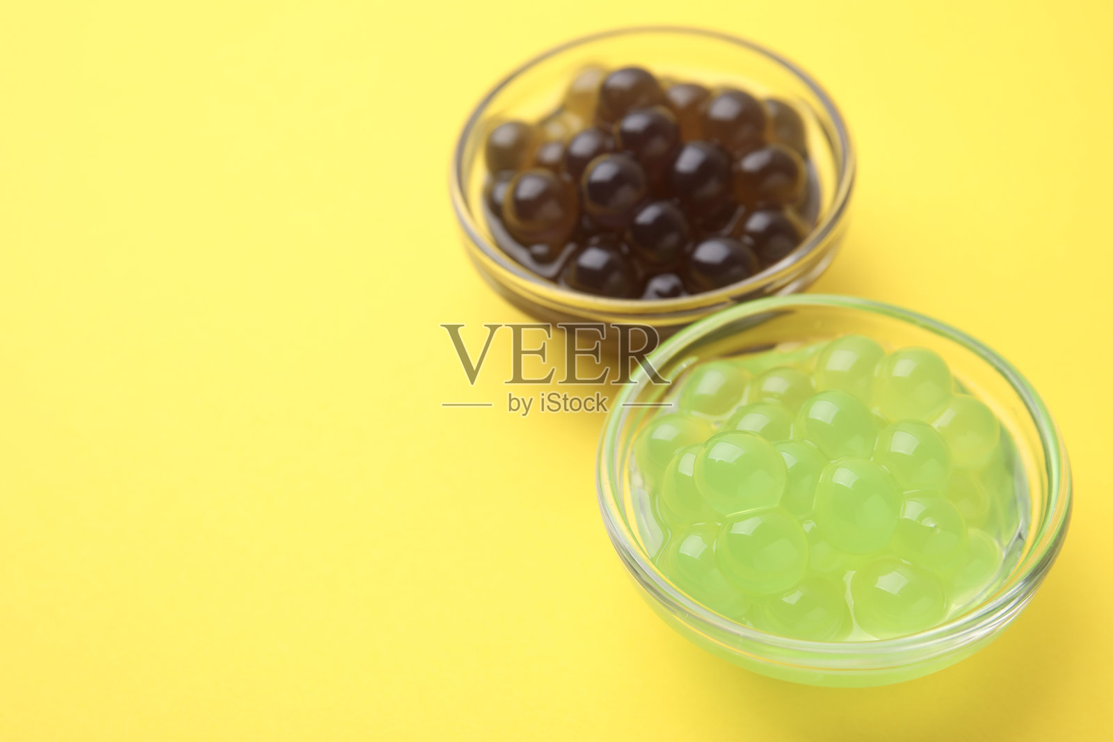 黄色背景上的彩色珍珠在碗中,特写。留有文本空间。照片摄影图片