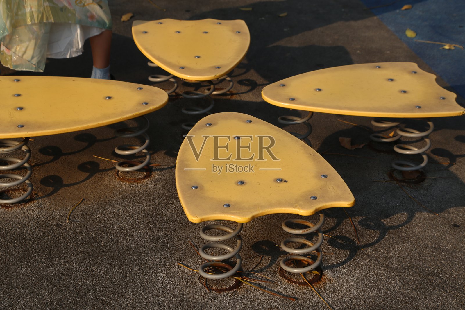 游乐场上儿童蘑菇形状的弹簧座椅,黄色带黑点,下面有金属弹簧。照片摄影图片