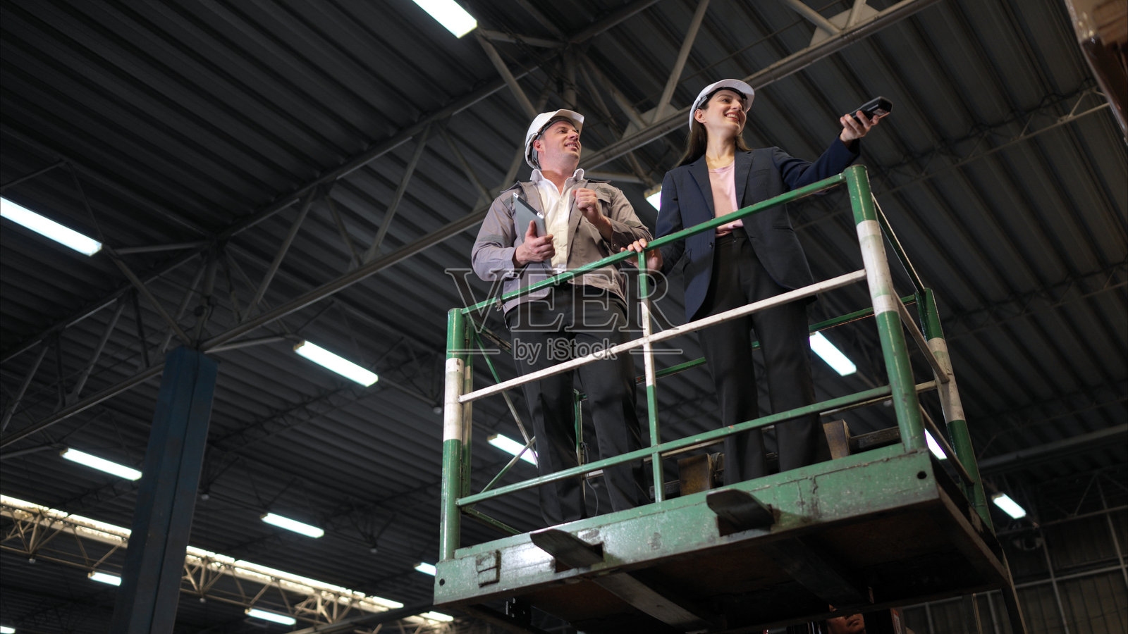 女商人与仓库工人正在根据文件审核物品清单照片摄影图片