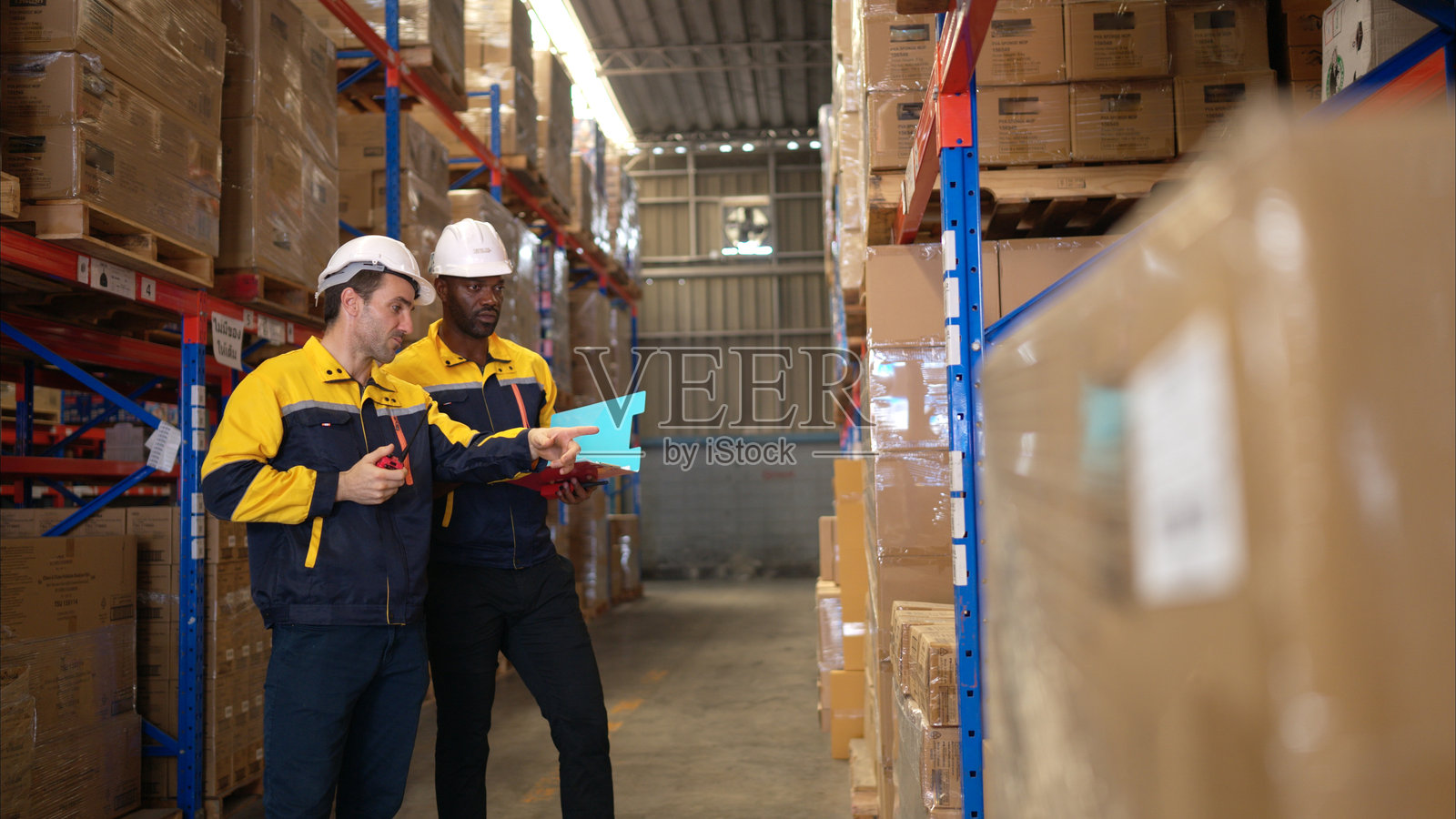 两名仓库工人正在根据文件审核物品清单照片摄影图片