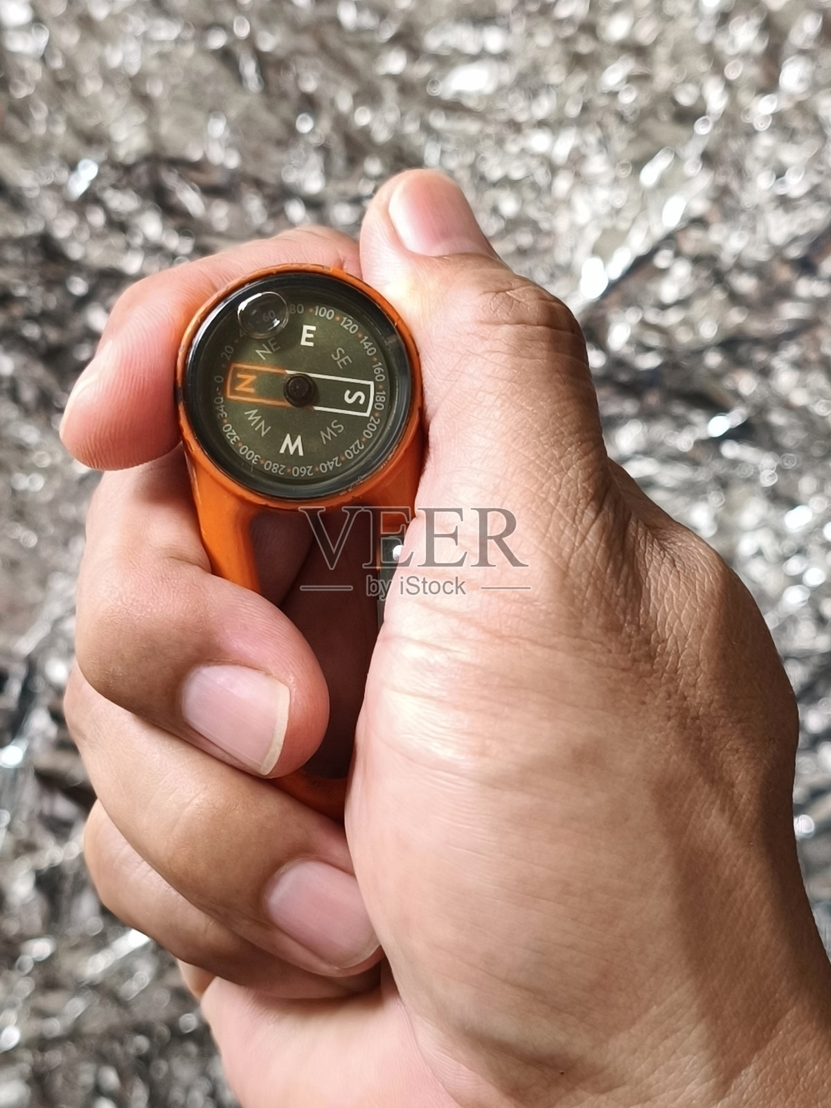 右手握着一个悬挂的指南针照片摄影图片