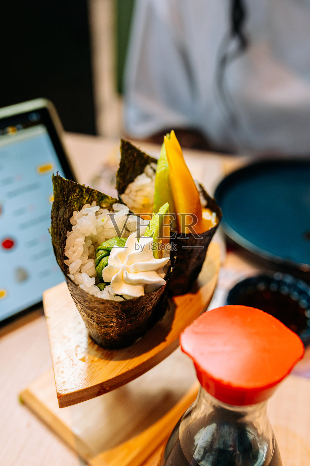 在餐厅里,手卷寿司卷配酱油被端上桌。照片摄影图片