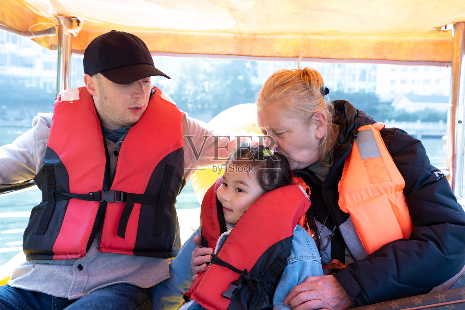 快乐的女孩和她的家人在湖上的船上照片摄影图片