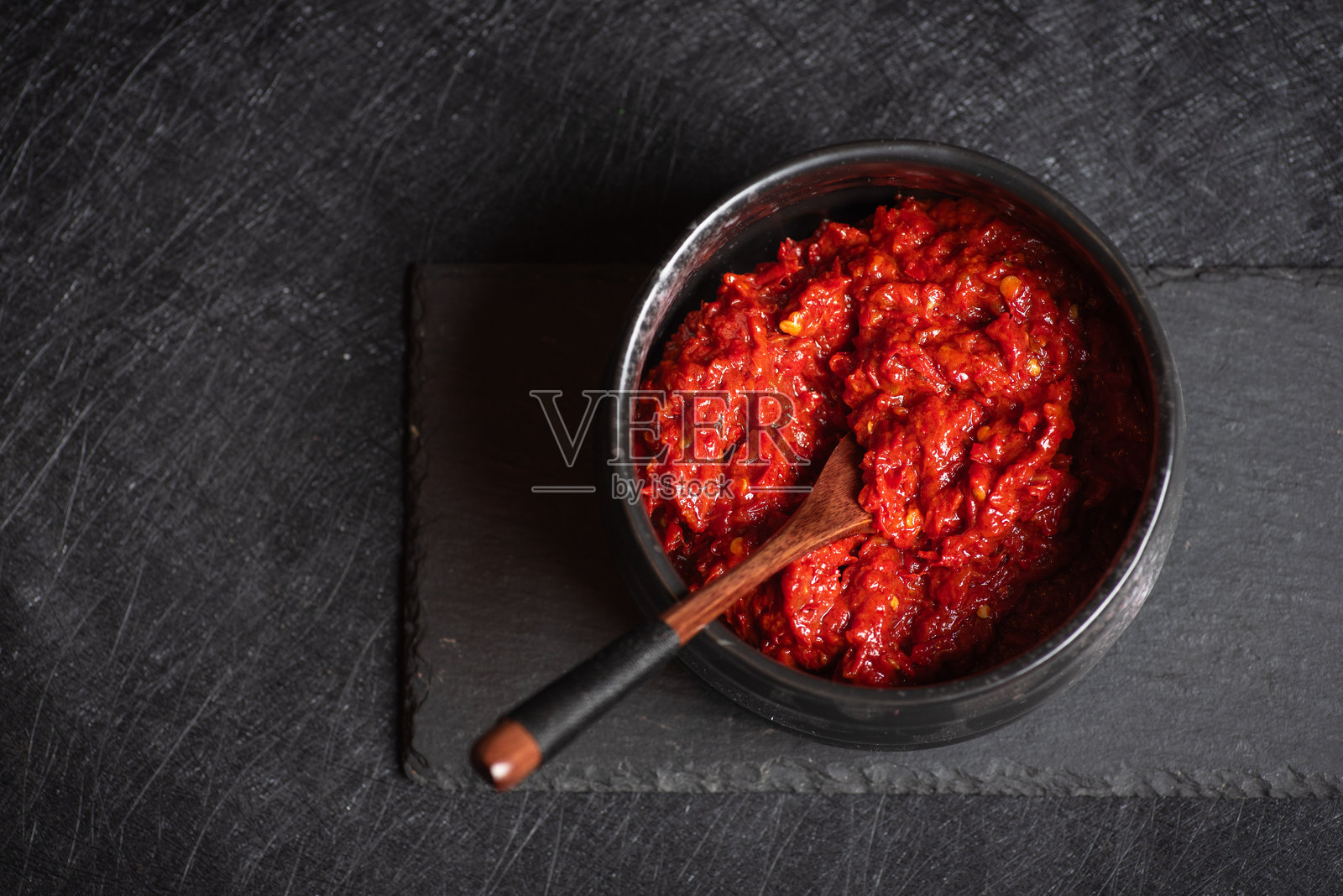 一碗阿伊瓦尔辣椒酱和一把木勺放在石板上照片摄影图片