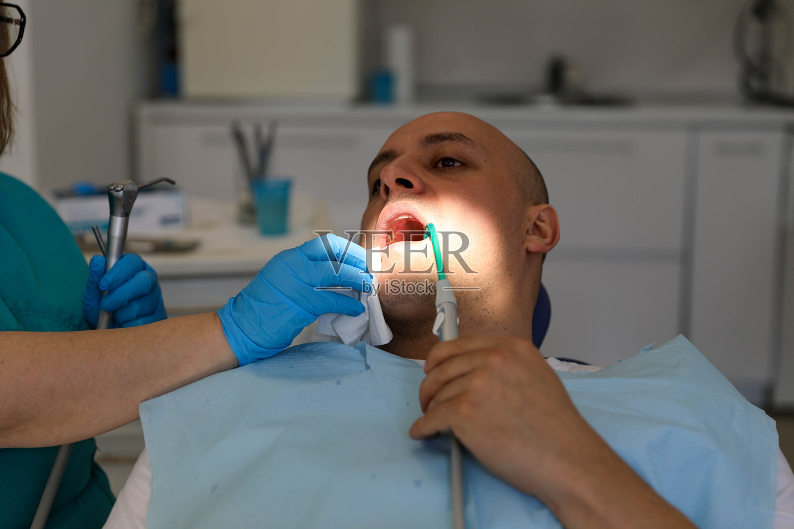 专业牙科护理:女性牙医在现代诊所为男性患者治疗照片摄影图片