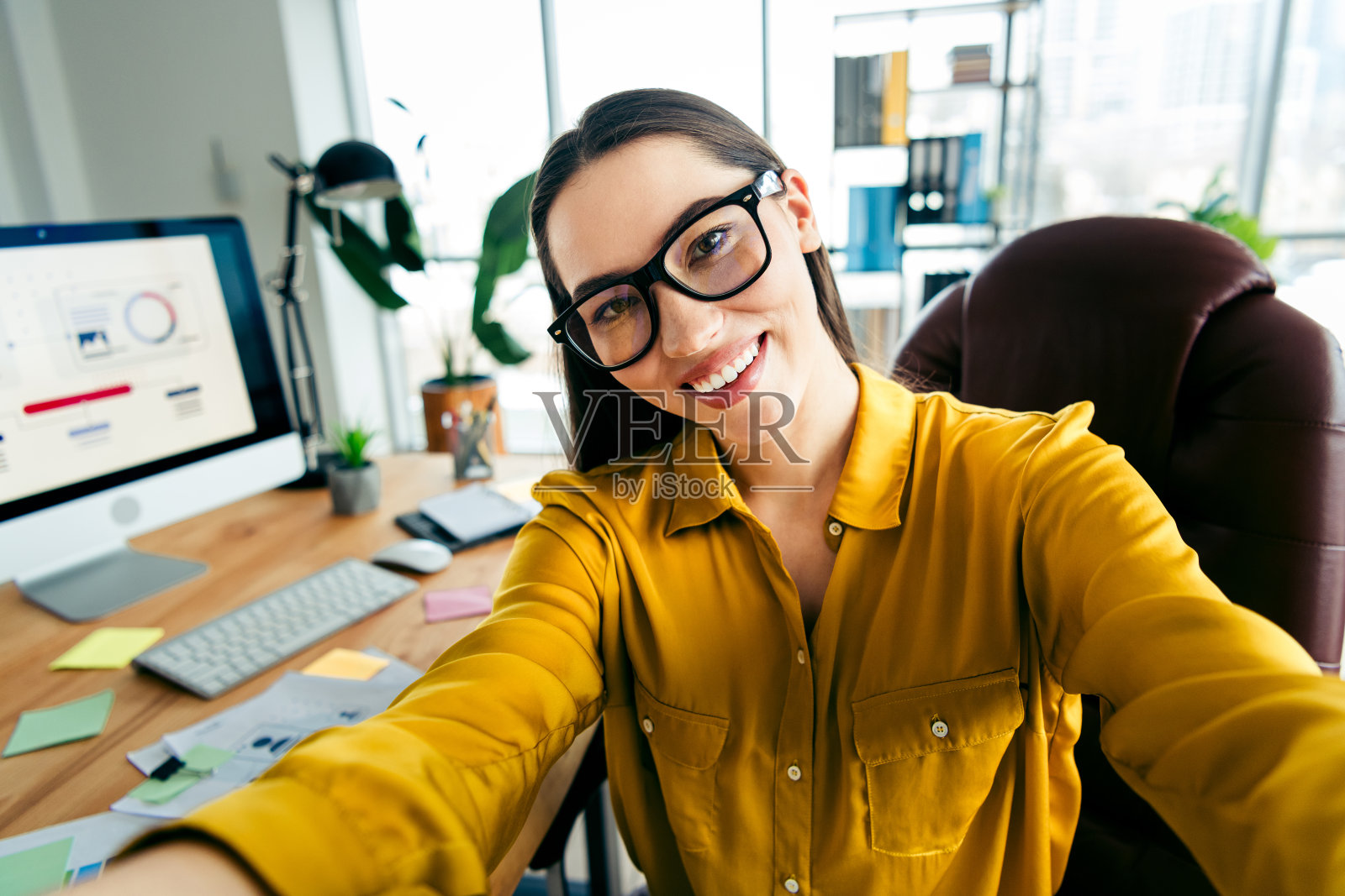 年轻职业女性在办公室工作区微笑,展示现代商业环境和专业精神照片摄影图片