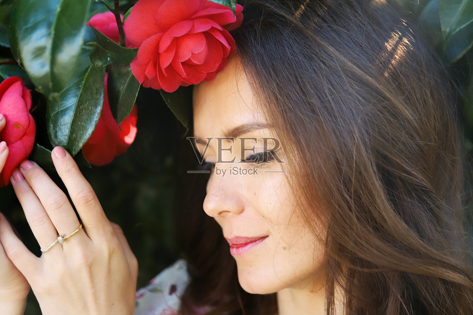 安静的棕发女性佩戴红色山茶花花冠照片摄影图片