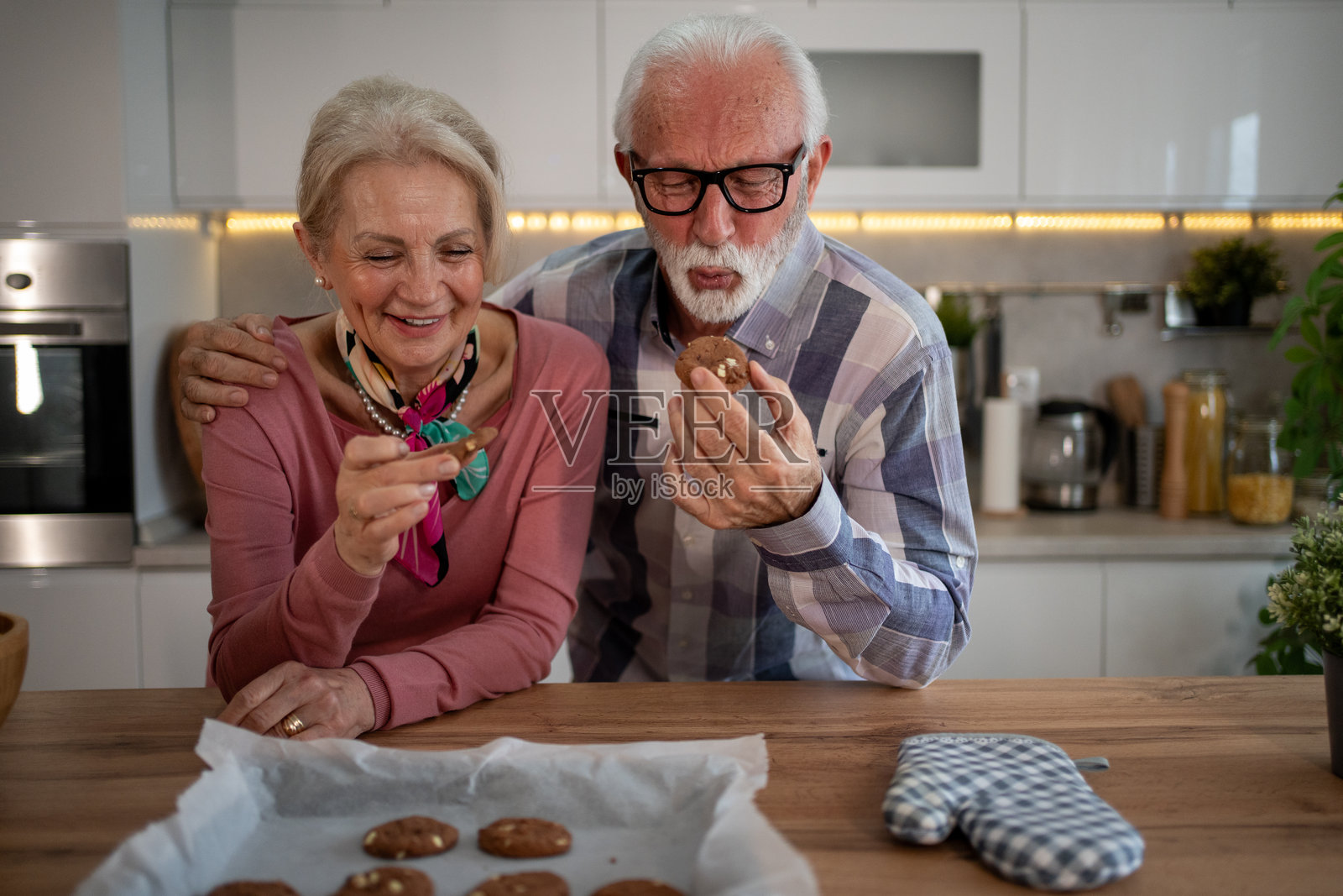 快乐的老年夫妇在厨房品尝新鲜出炉的饼干照片摄影图片