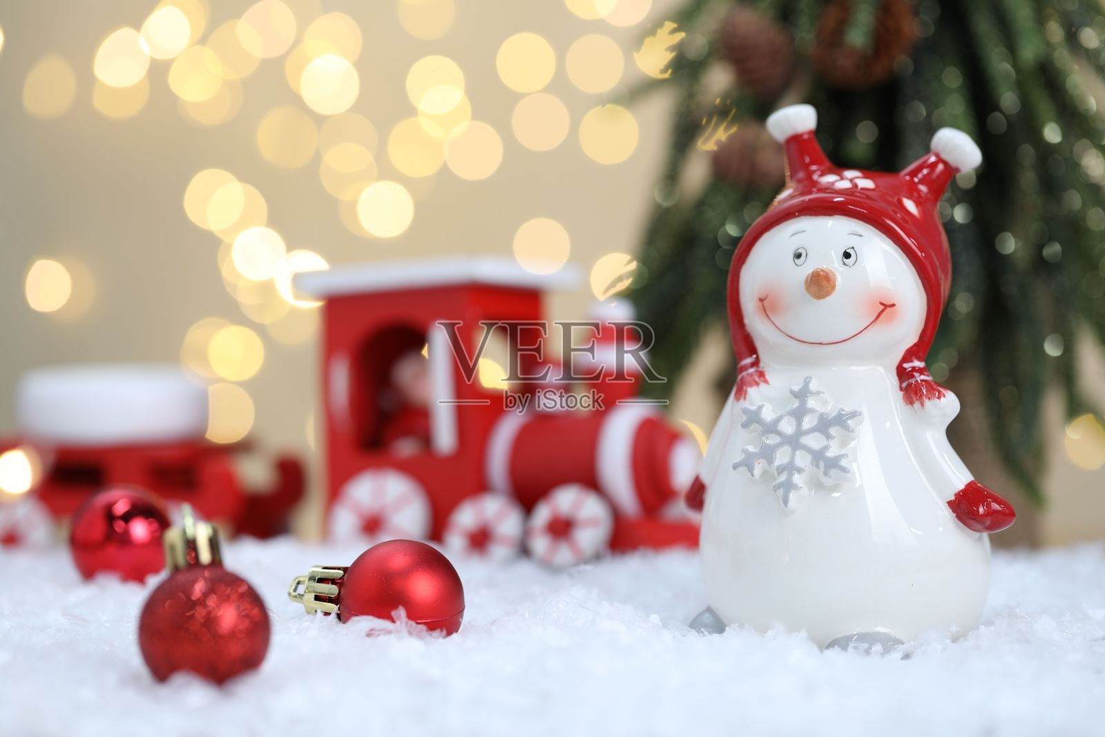 有趣的雪人造型和其他圣诞装饰在模糊灯光下的人造雪上照片摄影图片