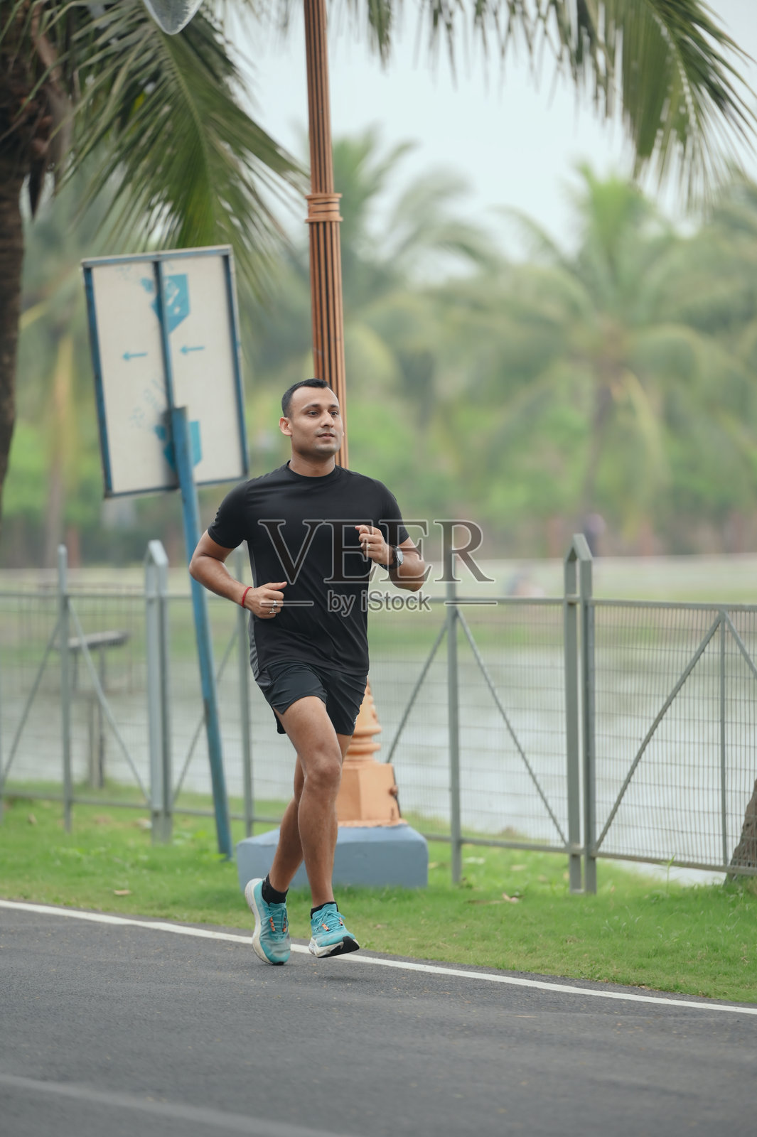在棕榈树环绕的跑道上奔跑的运动男士照片摄影图片