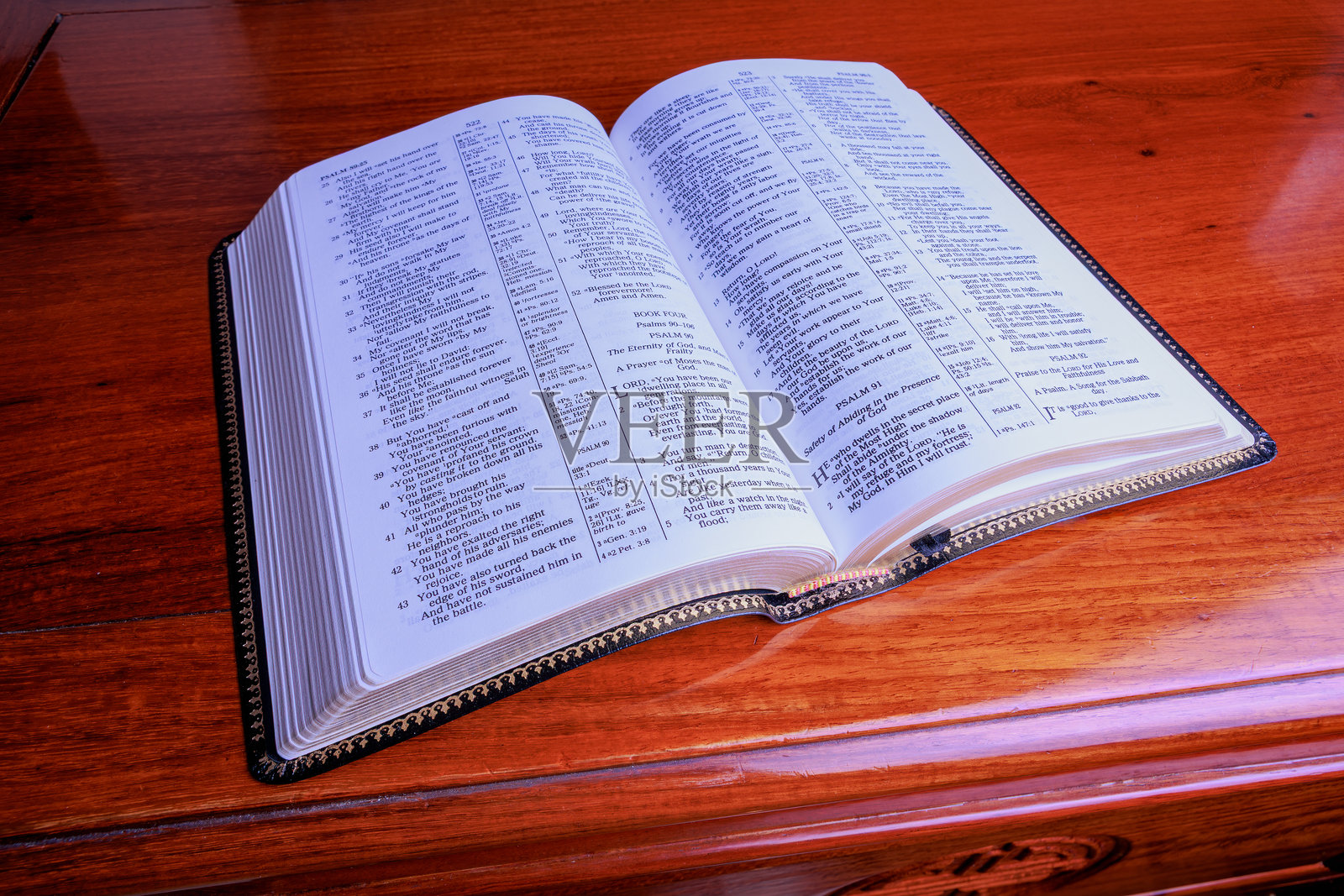 一本新修订的圣经,翻开在玫瑰木桌上,停留在诗篇91篇。照片摄影图片