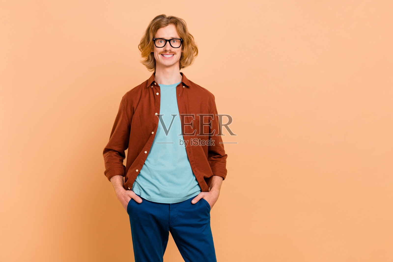 吸引人的快乐红发男孩双手插口袋,背景为米色柔和色调。照片摄影图片