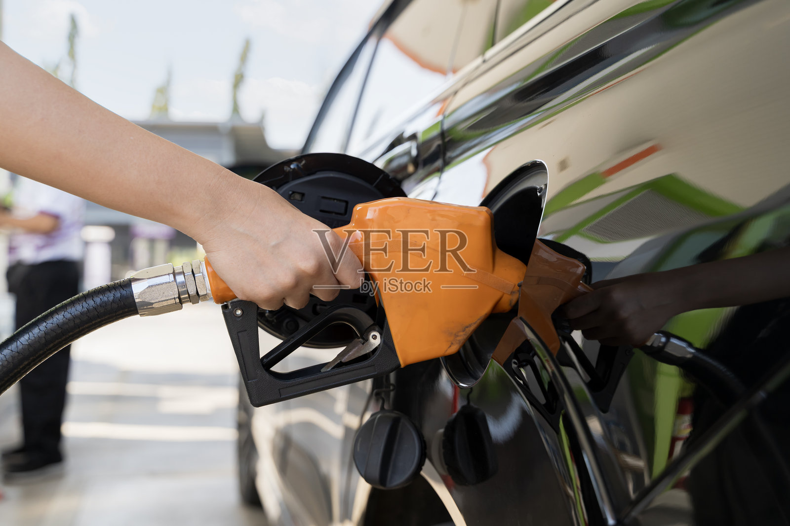 在能源危机期间,一位无法辨认的女性正在使用加油泵为她的汽车加油。照片摄影图片