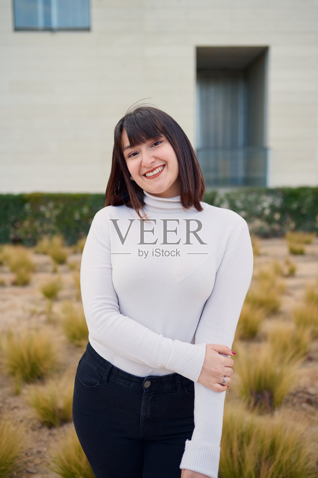 年轻女性在现代建筑前微笑并摆姿势照片摄影图片