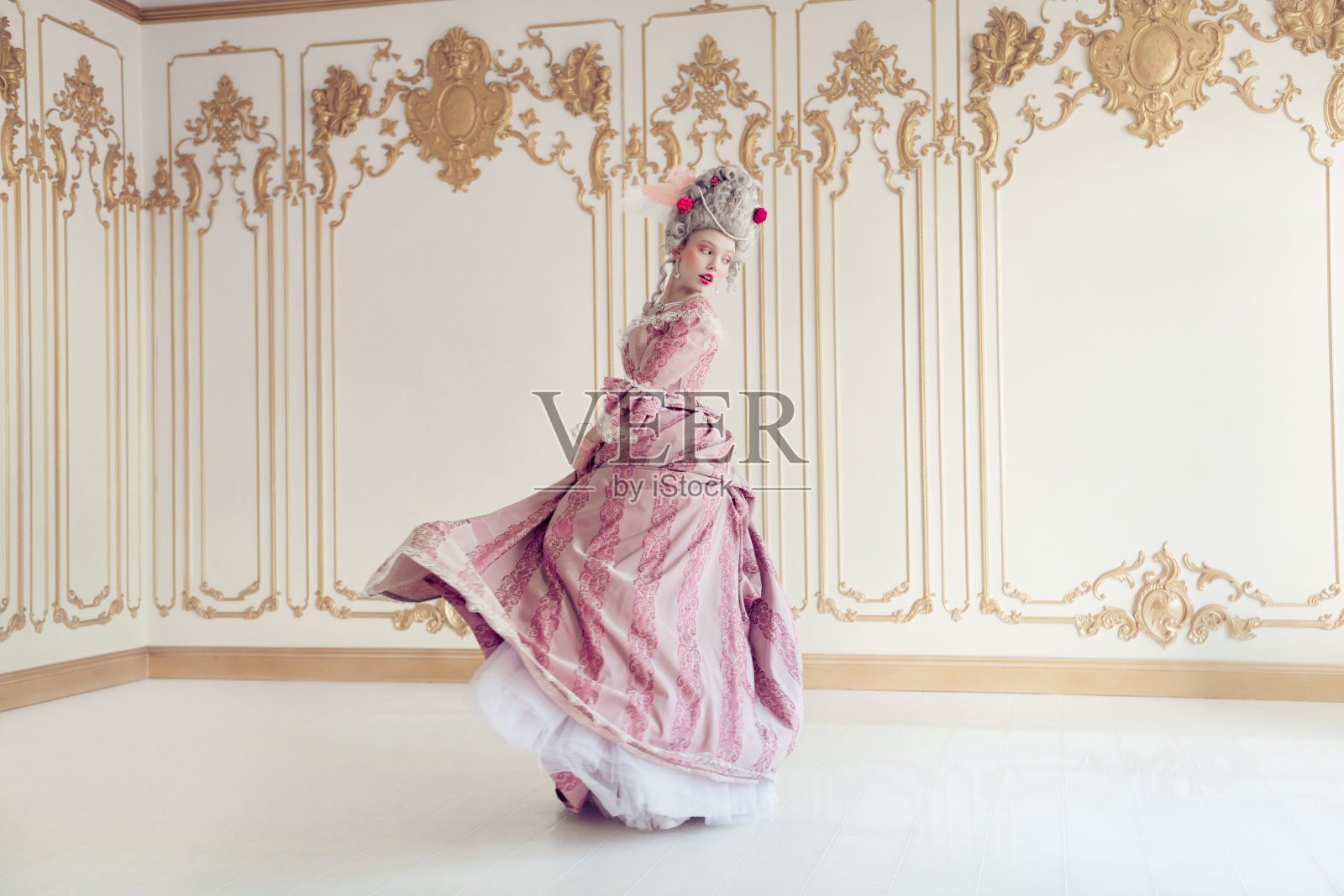 一位年轻女性身着优雅的巴洛克风格长裙,在复古房间中优雅地旋转,融合了过去与现在的风格。照片摄影图片