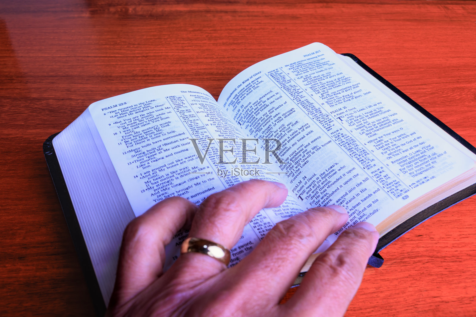 在玫瑰木桌上放着一本小型新修订版圣经,翻开在诗篇23篇。照片摄影图片