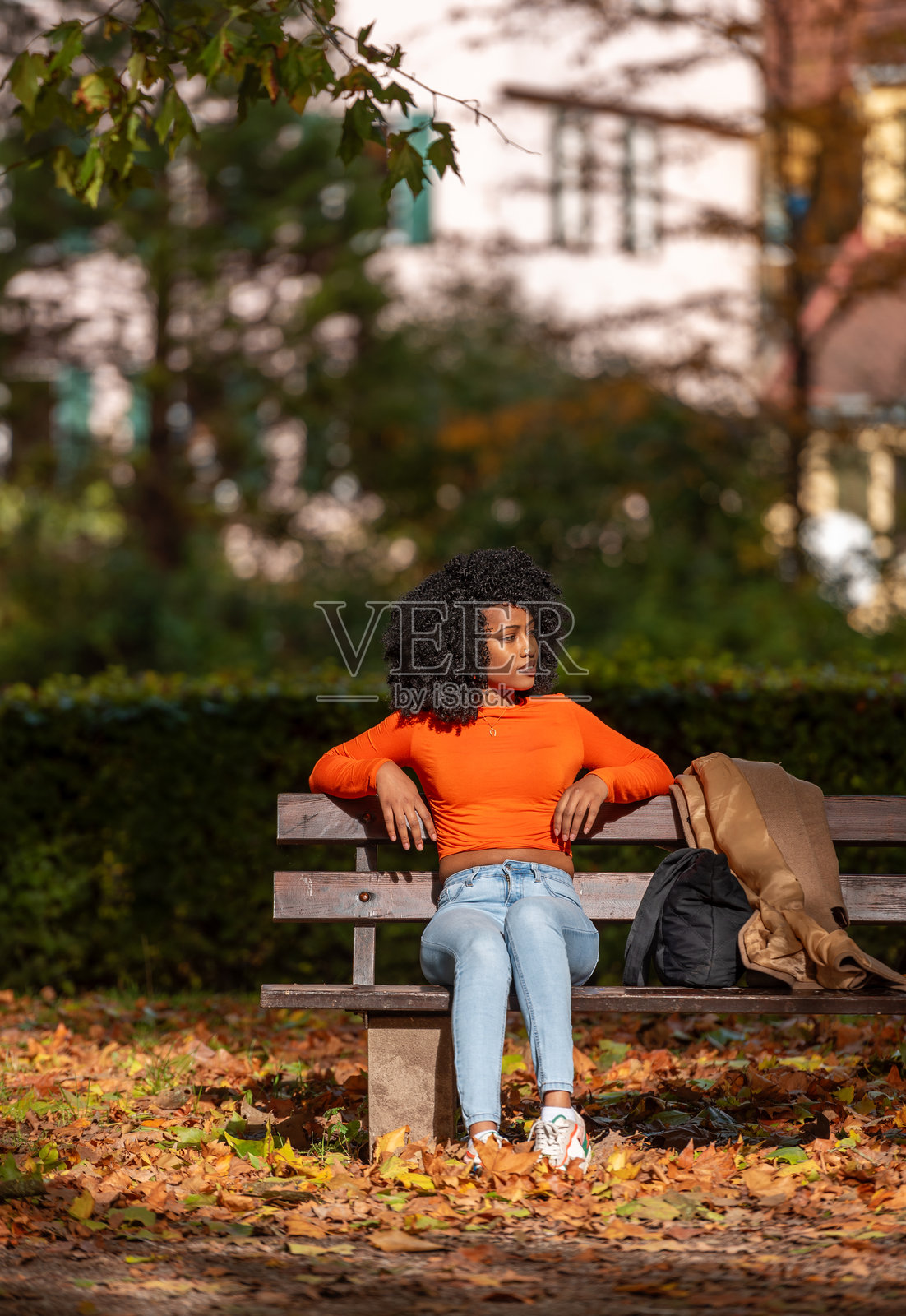 德国图宾根的秋季风景中,Z世代女性在公园长椅上放松。照片摄影图片