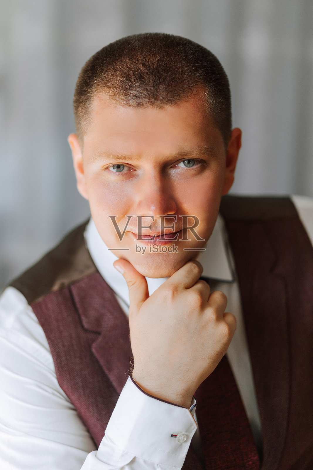 一位穿着西装和马甲的男士面带微笑地看着镜头。照片摄影图片