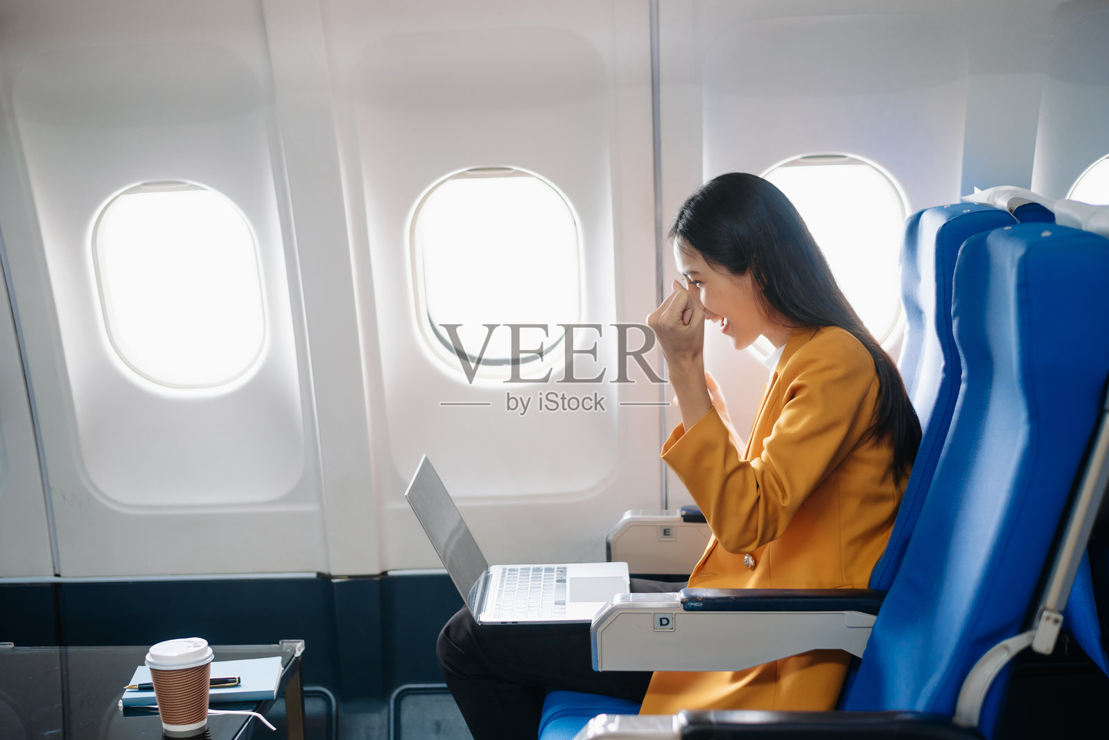 亚洲女性坐在飞机座位上,望着窗外,享受旅行度假的概念照片摄影图片