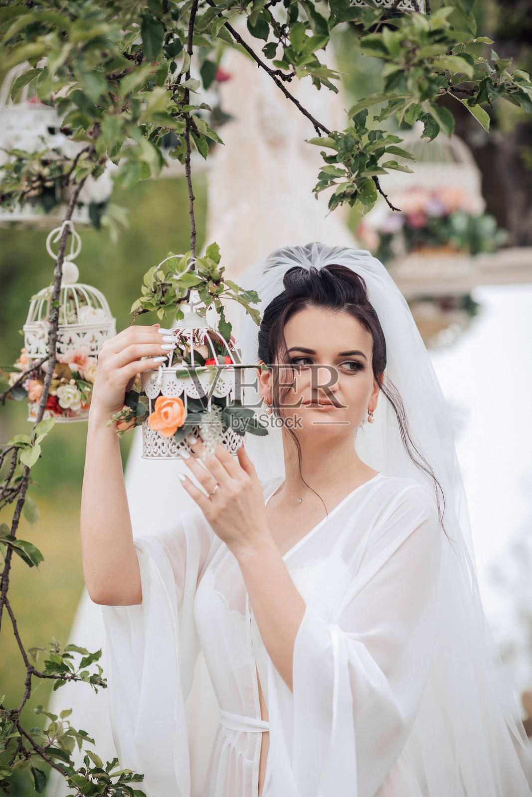 一位女士手里拿着一个装有花朵的鸟笼照片摄影图片