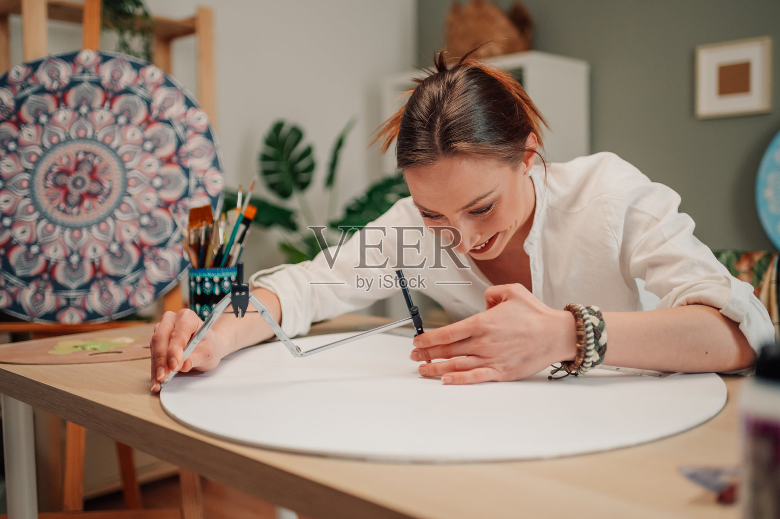 年轻艺术家在她的工作室里用圆规画圆。照片摄影图片