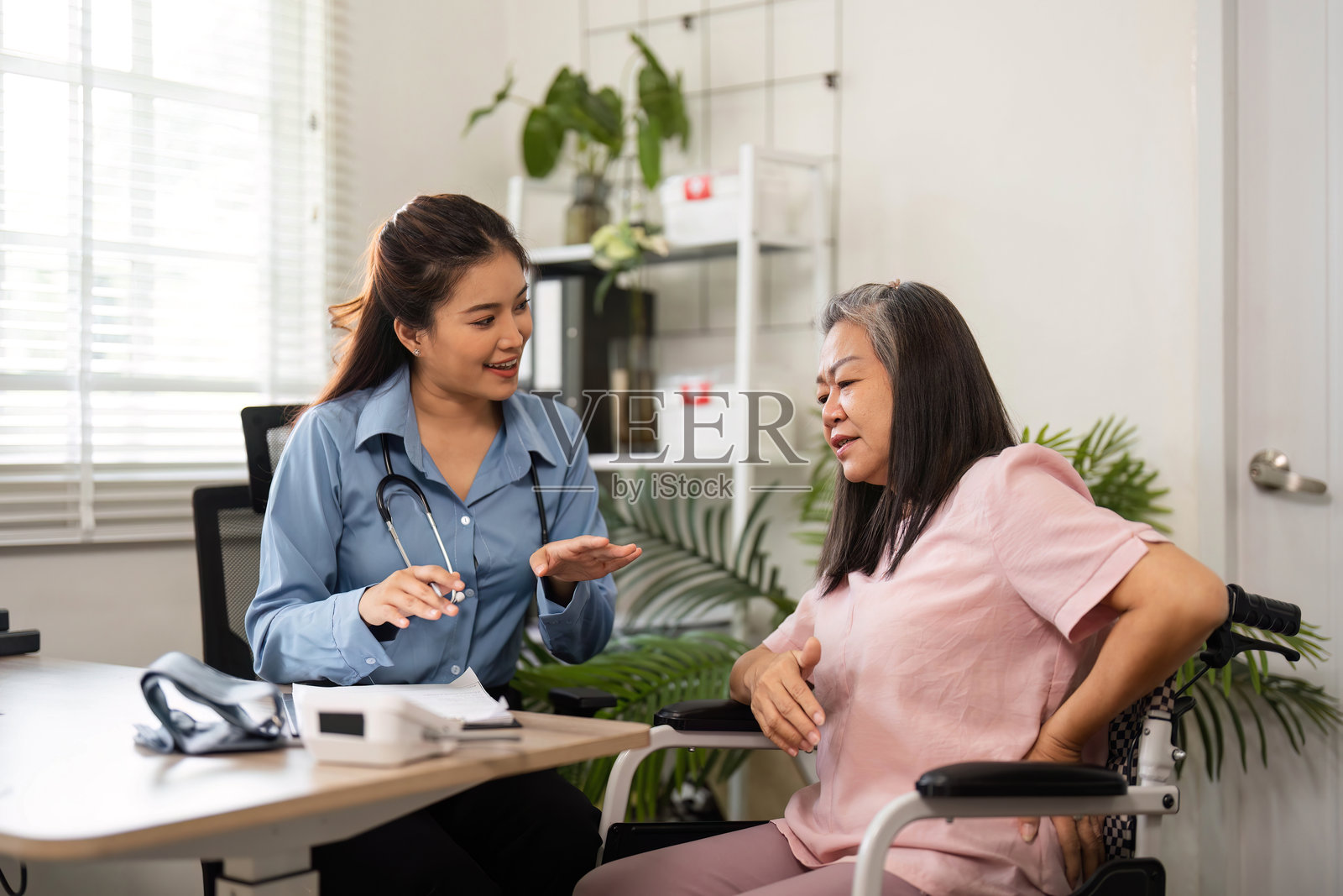 护士在一个温馨的诊所为一位老年患者提供护理和健康建议。照片摄影图片