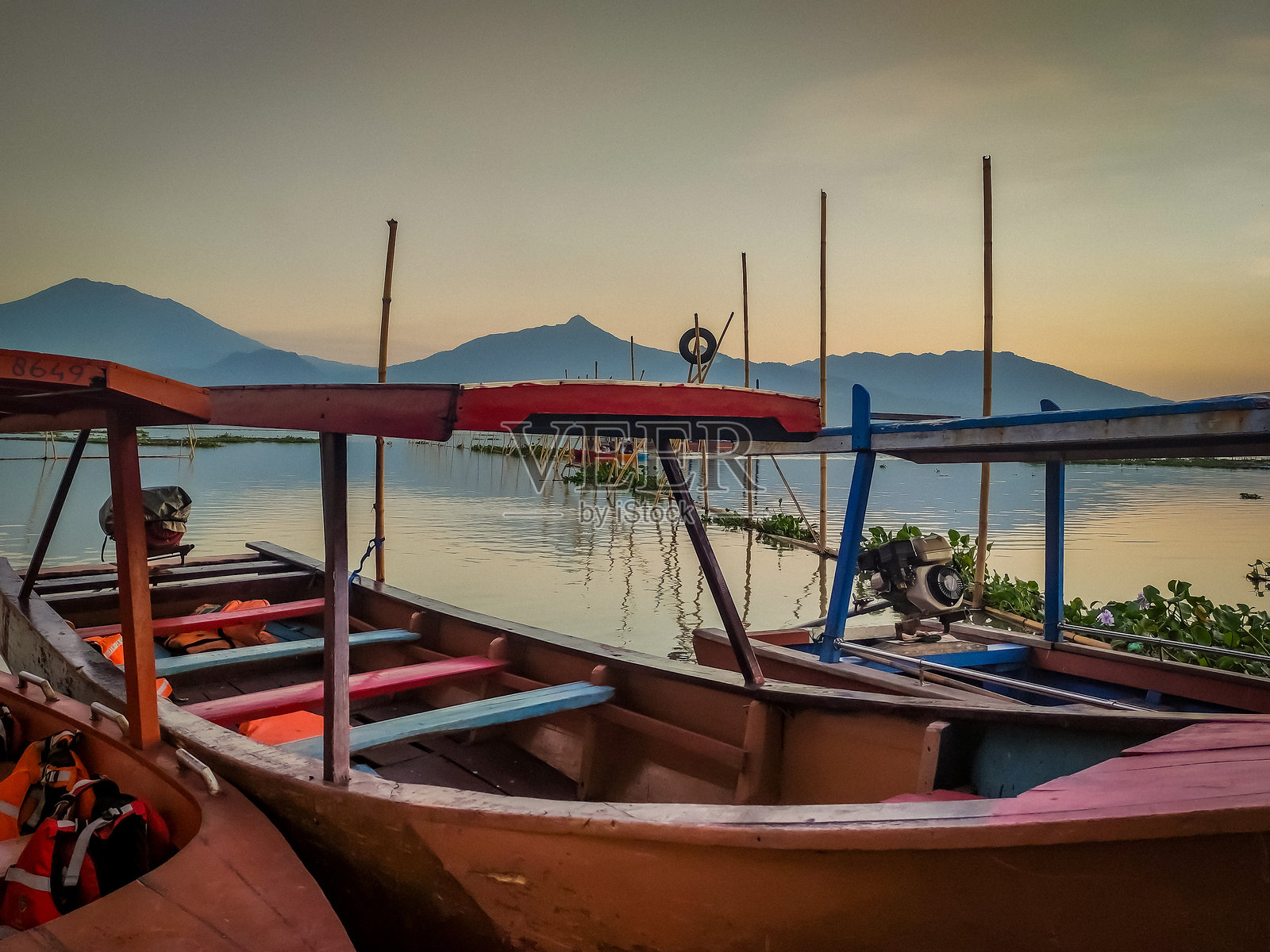 日落时分,五彩斑斓的船只在宁静的拉瓦佩宁湖上,远处可见梅尔巴布、加贾特洛莫约山脉的景色。照片摄影图片