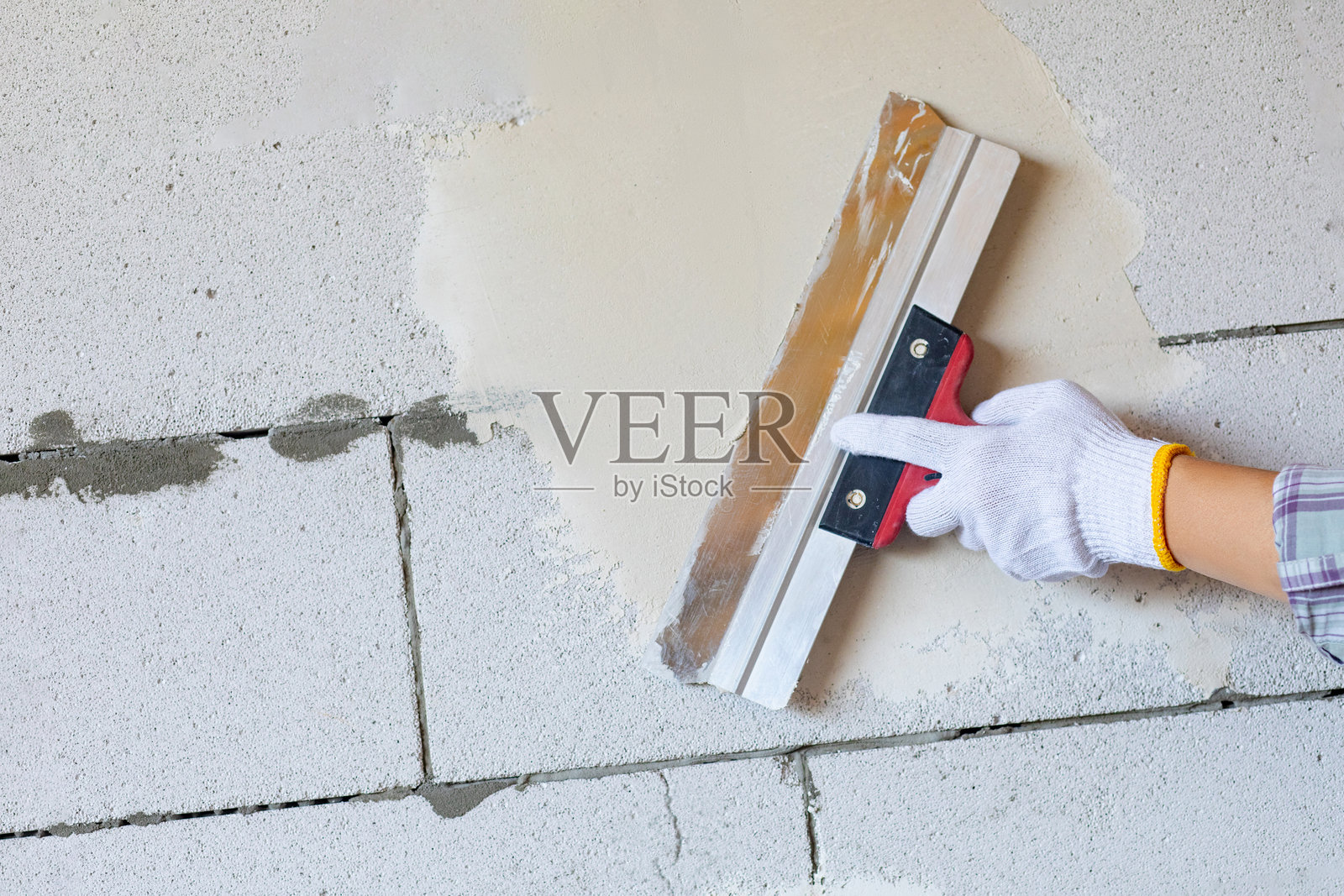 工匠在墙壁上涂抹腻子。照片摄影图片