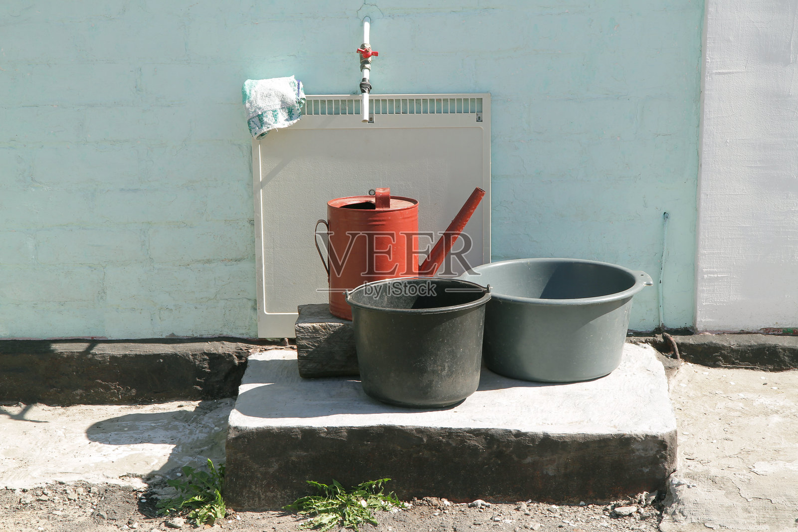 花园浇水器和水桶靠近户外水龙头。照片摄影图片