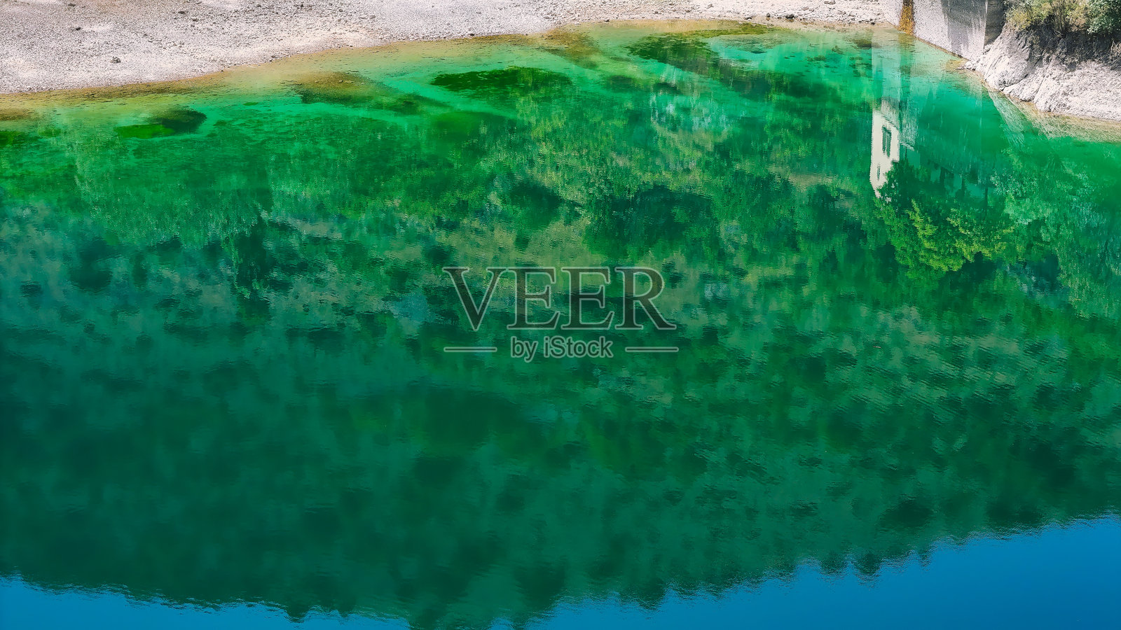 宁静的湖水映照着郁郁葱葱的绿树,位于大自然中心的宁静湖畔,蓝天清澈。照片摄影图片