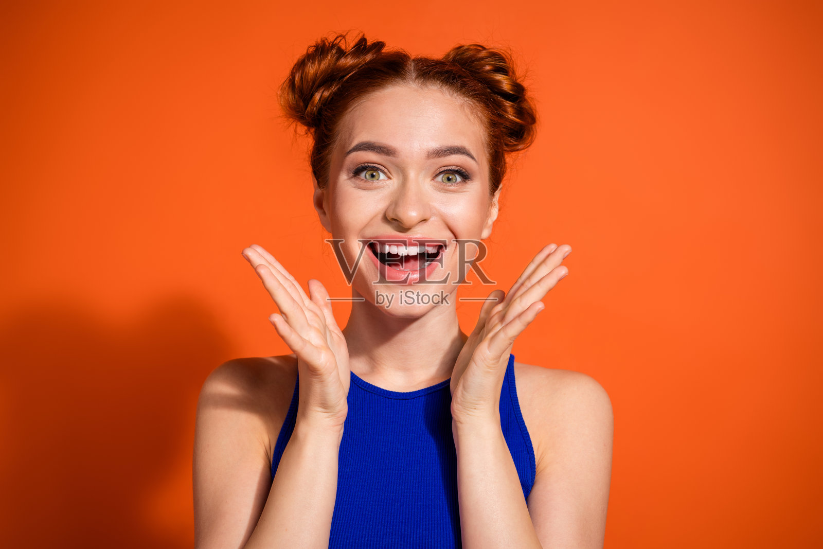 充满活力的年轻女性,时尚的红发在鲜艳的橙色背景下兴奋地做手势照片摄影图片