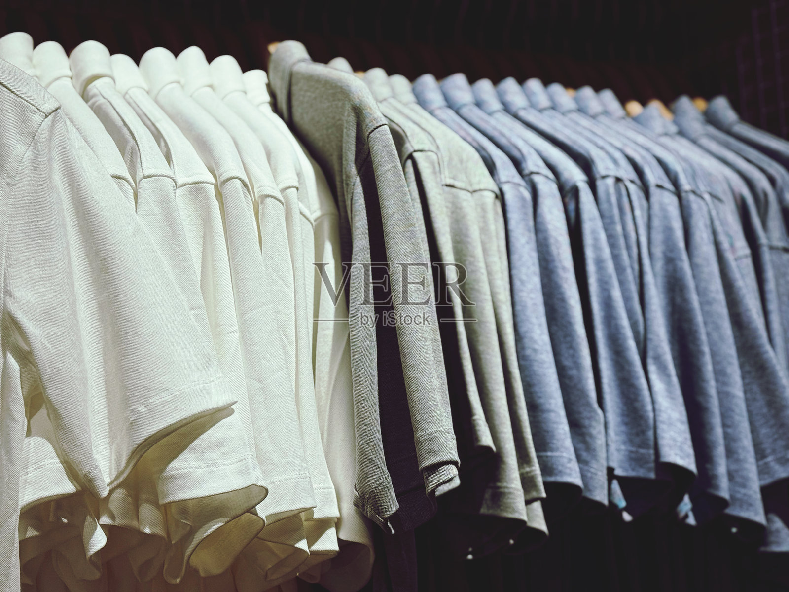 商店里的男士T恤挂在衣架上。照片摄影图片