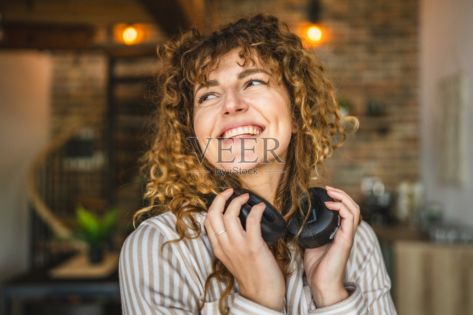 微笑的成年女性在家中佩戴耳机听音乐的肖像照片摄影图片