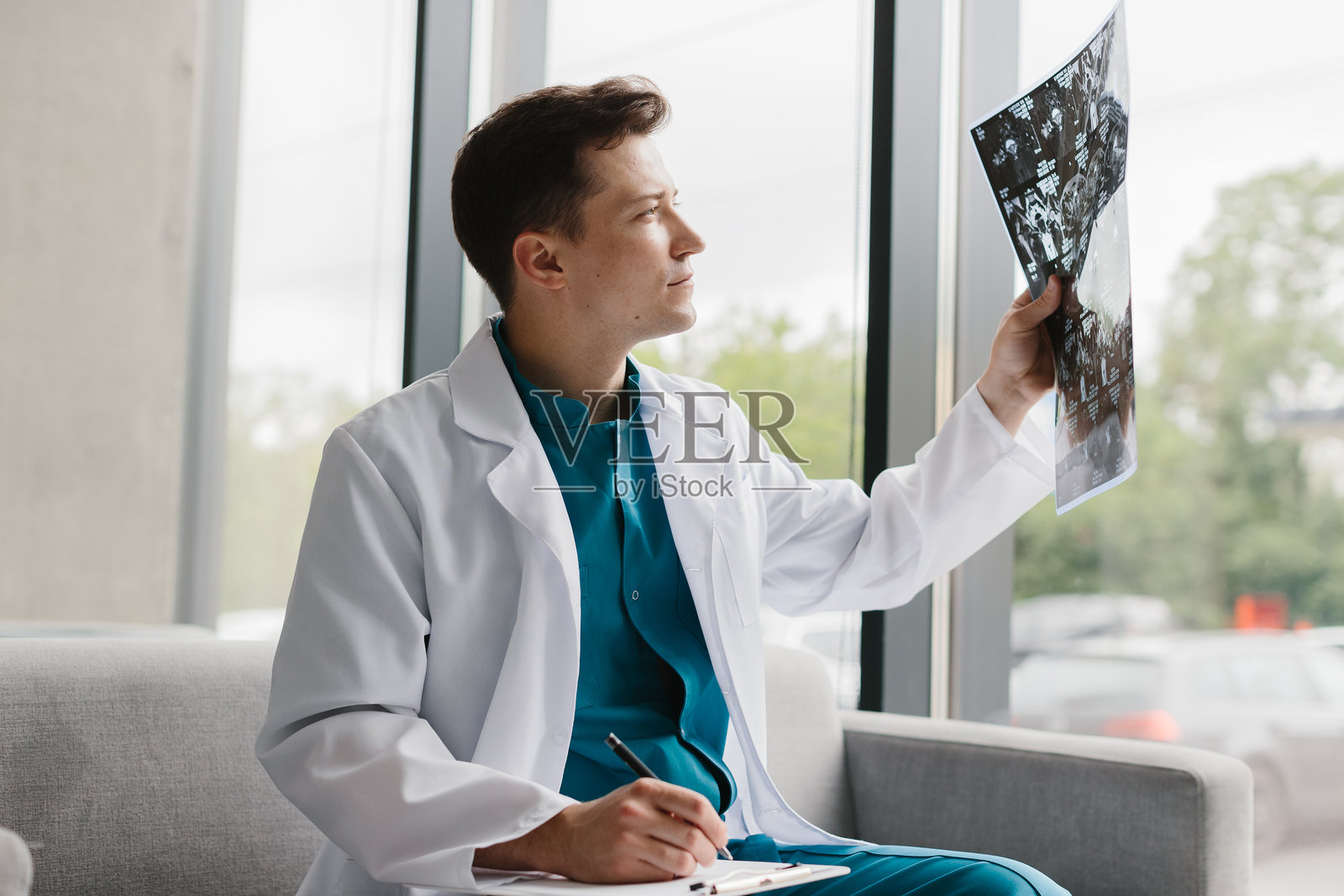 年轻医生在现代诊所分析X光图像。照片摄影图片