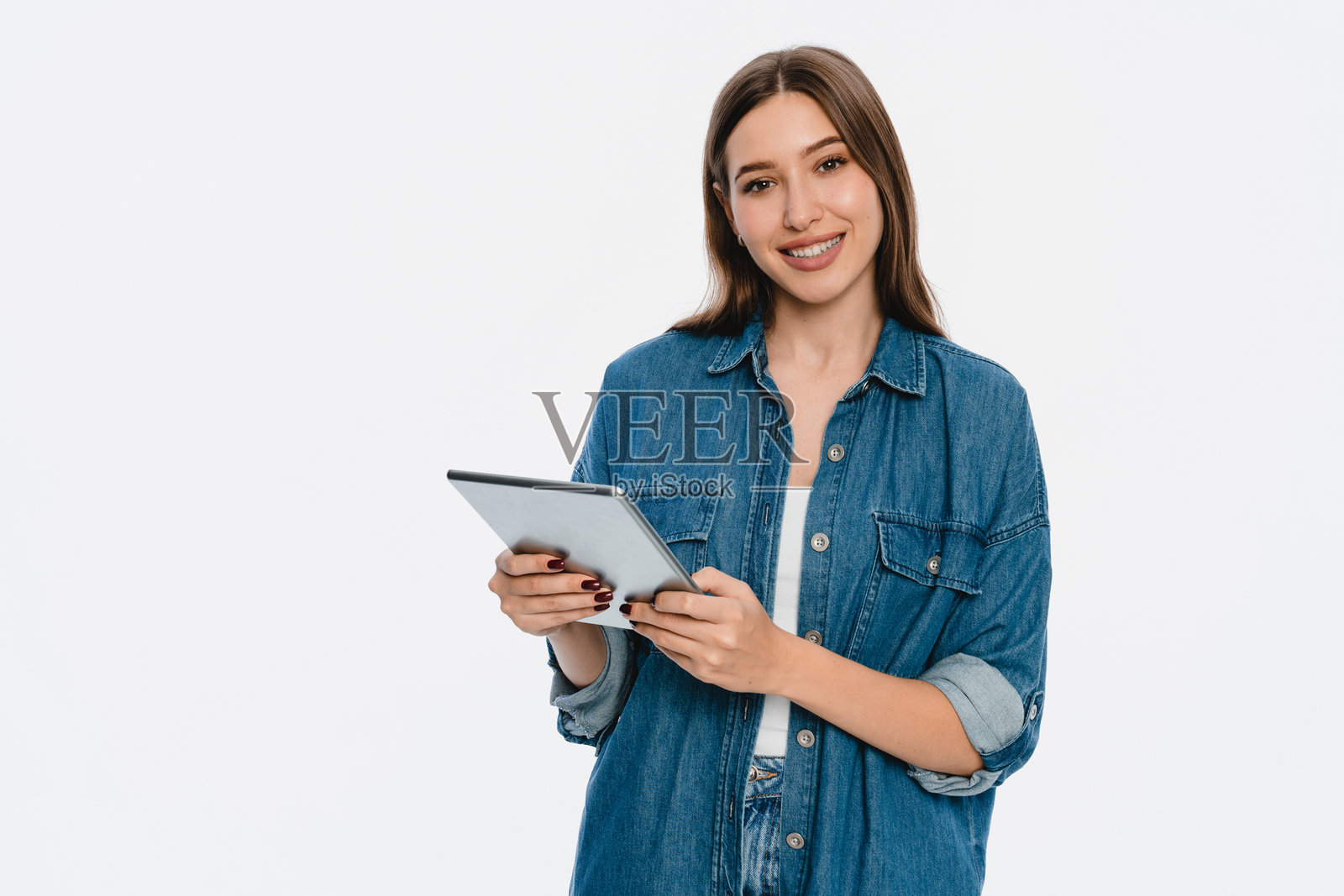微笑的女性穿着休闲牛仔服,手持平板电脑照片摄影图片