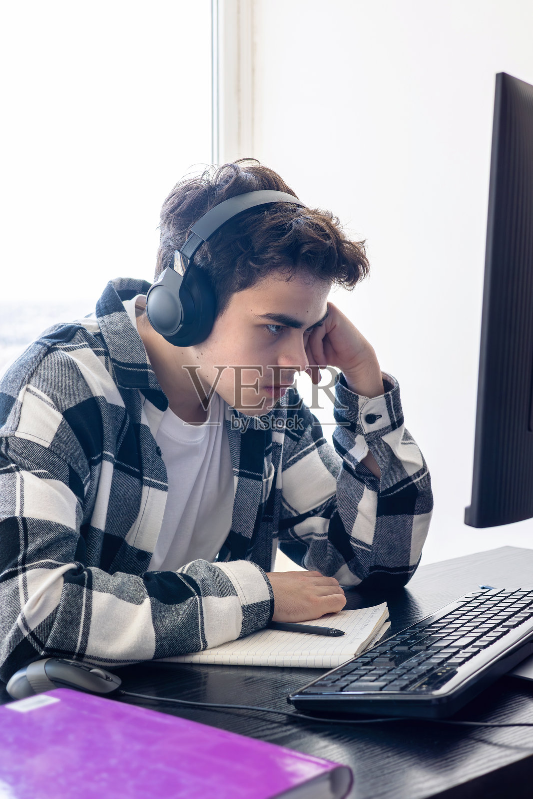 感到压力的青少年学生坐在桌子前,面前有电脑,因考试准备和在线学习而感到不堪重负。数字过载、教育疲惫、注意力缺陷多动障碍和心理疲劳的概念。照片摄影图片