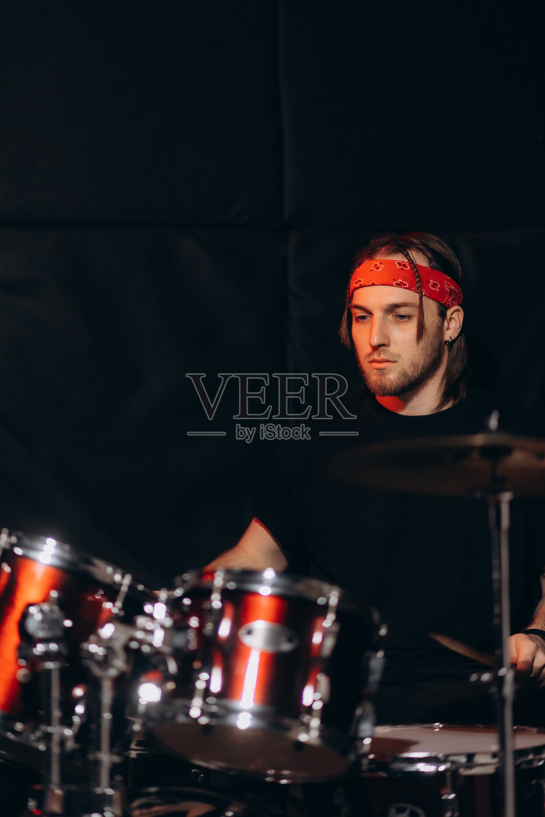 年轻音乐家在录音室环境中专注地打鼓表演照片摄影图片