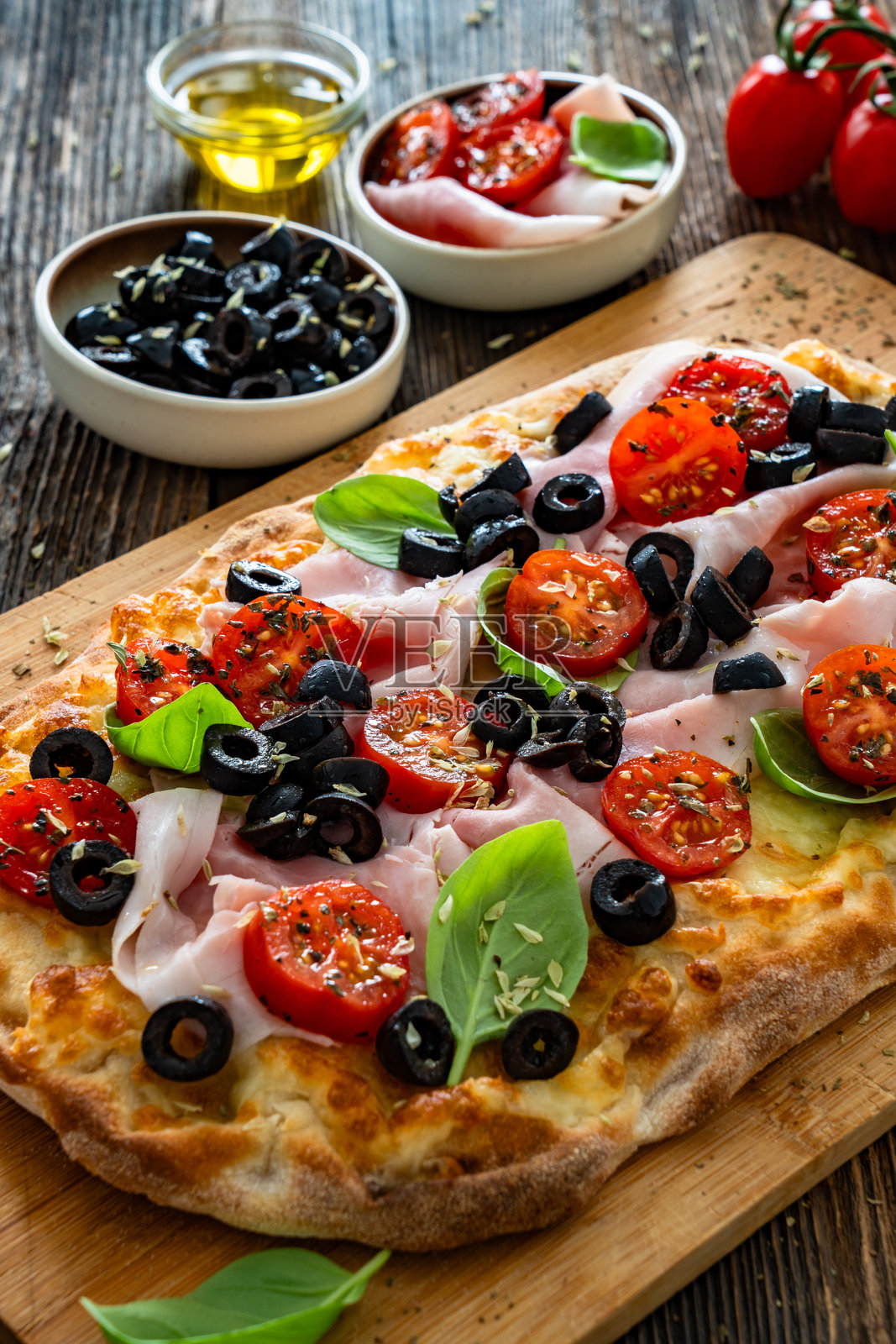罗马披萨,上面有熟火腿、马苏里拉奶酪和蔬菜,放在木桌上照片摄影图片