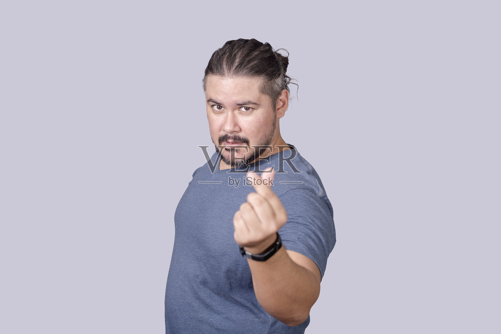 一位30多岁的胡子男人做出心形手势。背景为灰色。照片摄影图片