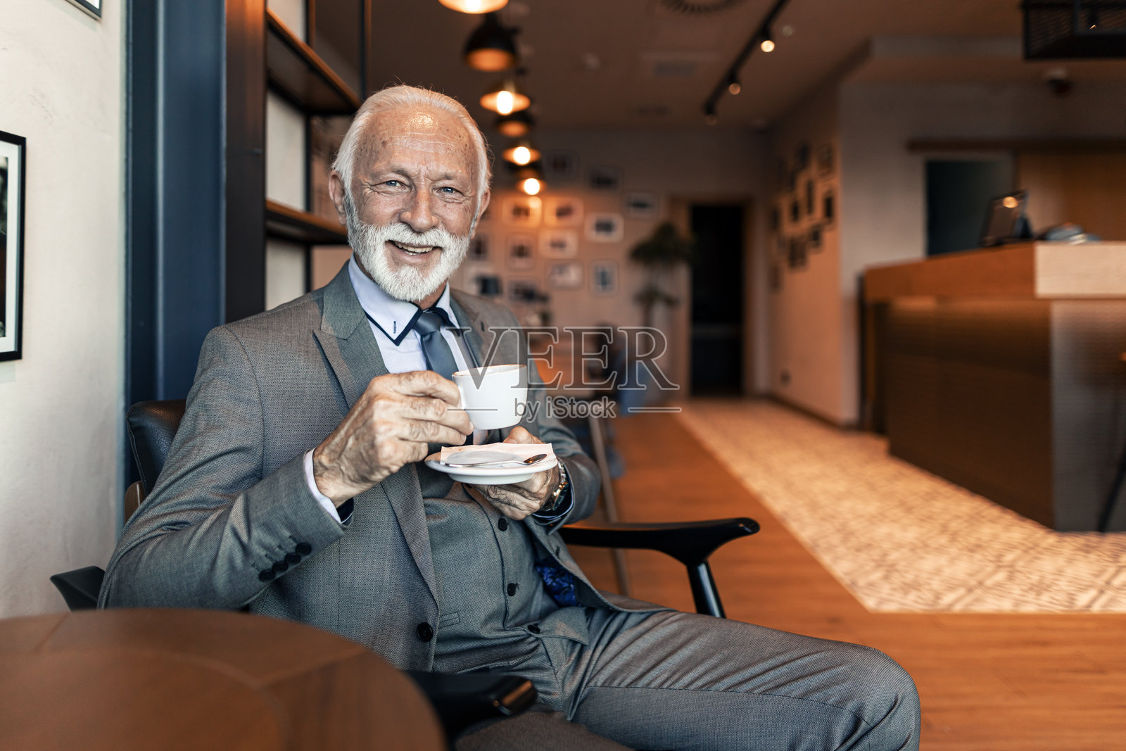 现代咖啡馆中微笑着享受咖啡的资深商人照片摄影图片