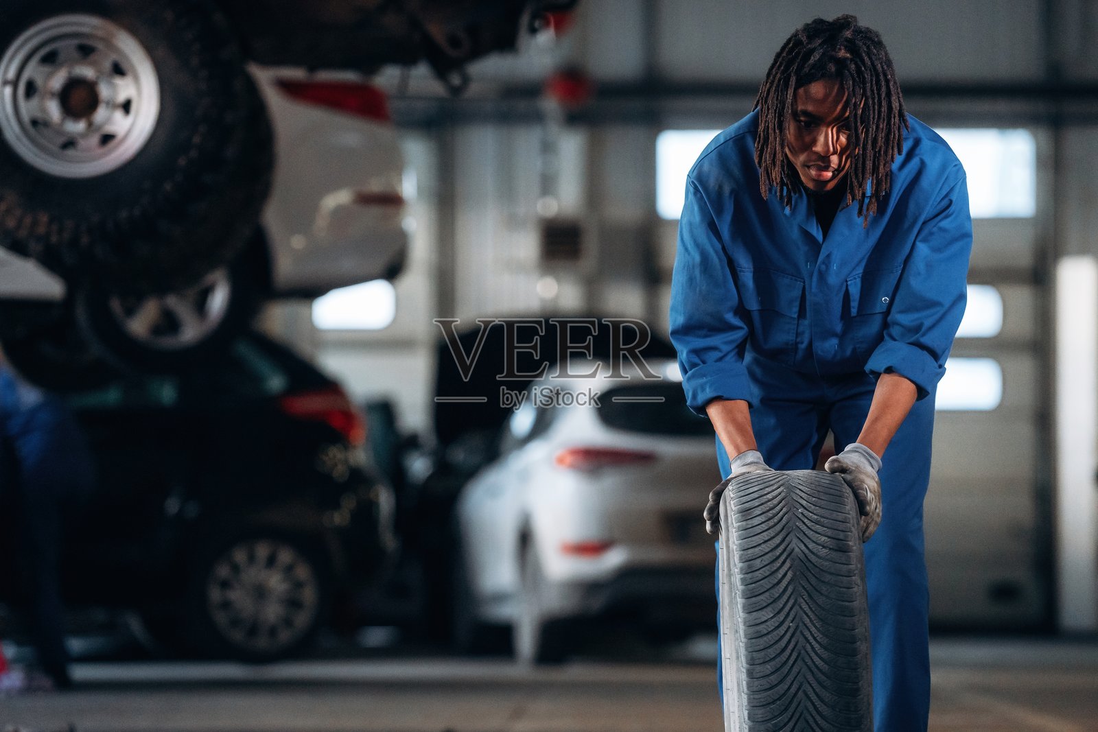 男性机械师在车库里与汽车一起。照片摄影图片